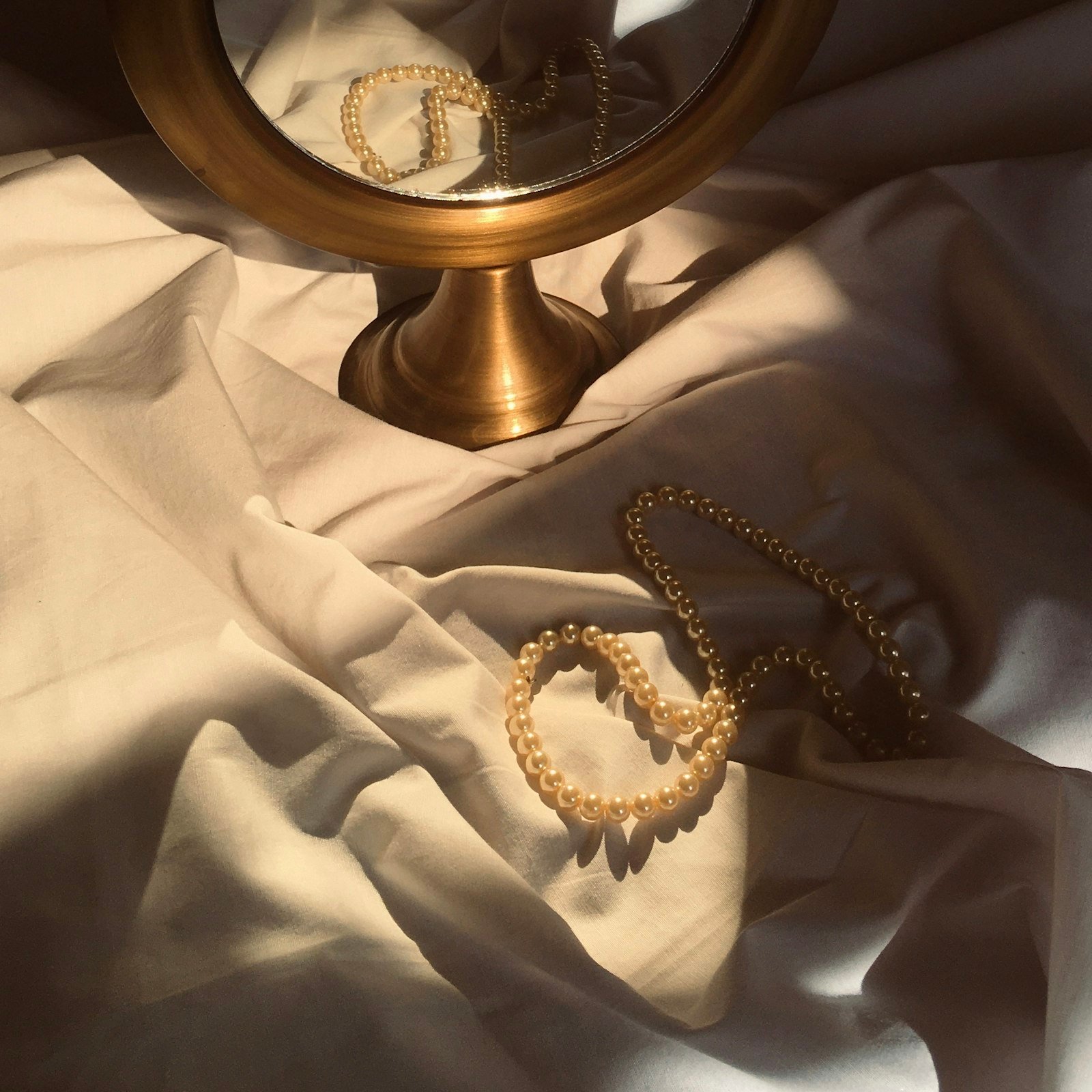 Gold-framed mirror on soft fabric